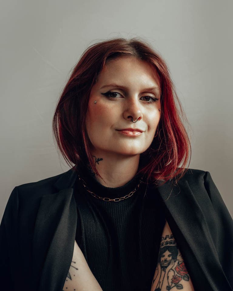 Mulher de cabelos vermelhos e tatuada em fotografia de estúdio, transmitindo confiança e sutileza, capturado em ensaio fotográfico em Joinville