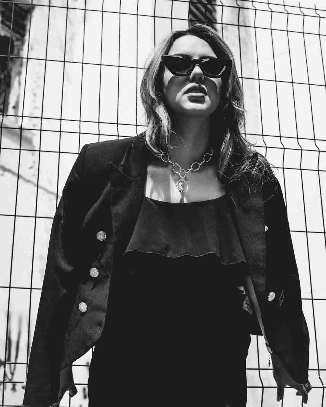 Fotografia feminina em estúdio: mulher confiante em look preto com salto e jaqueta